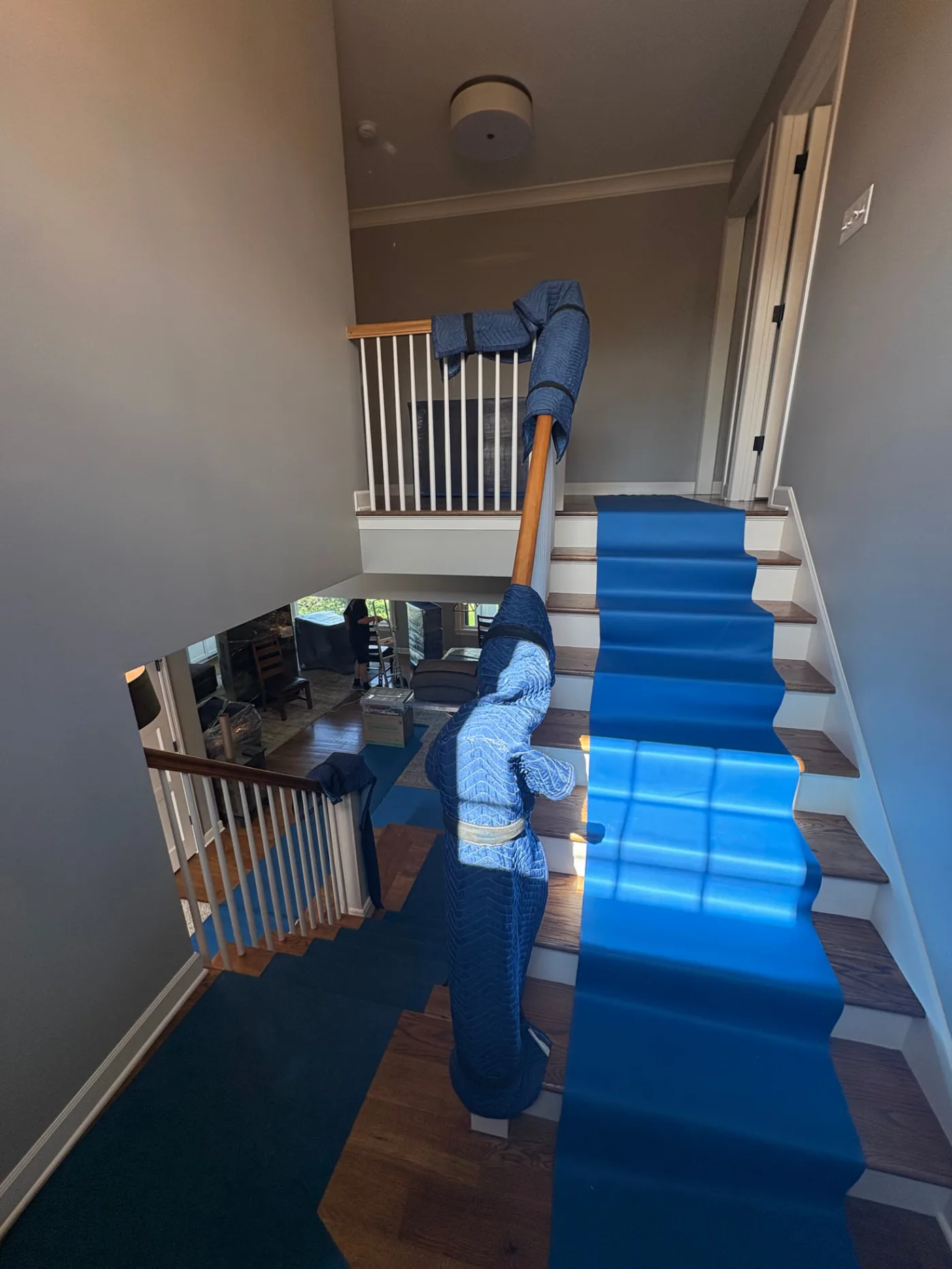 Dahlberg's Moving crew protecting hardwood stairs and floors with runners while carrying wrapped furniture